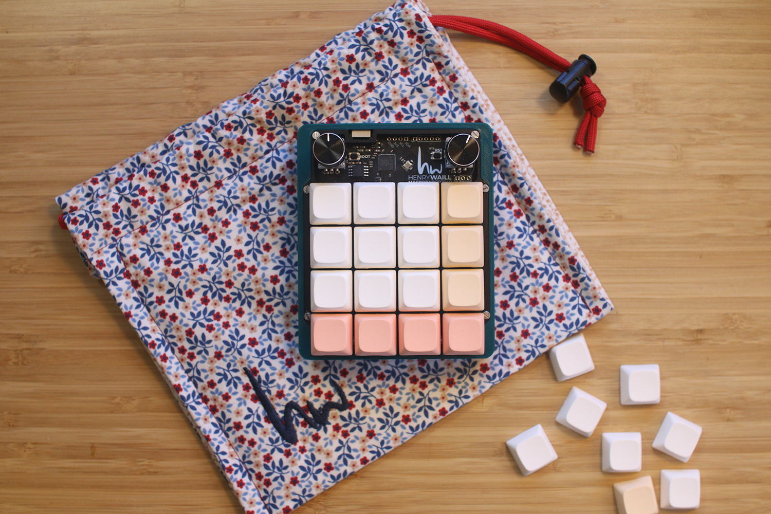 Birdseye image shows the macropad 2040 keypad on a desk surface. It rests on its hand-sewn pouch, and extra keycaps lay scattered next to it.