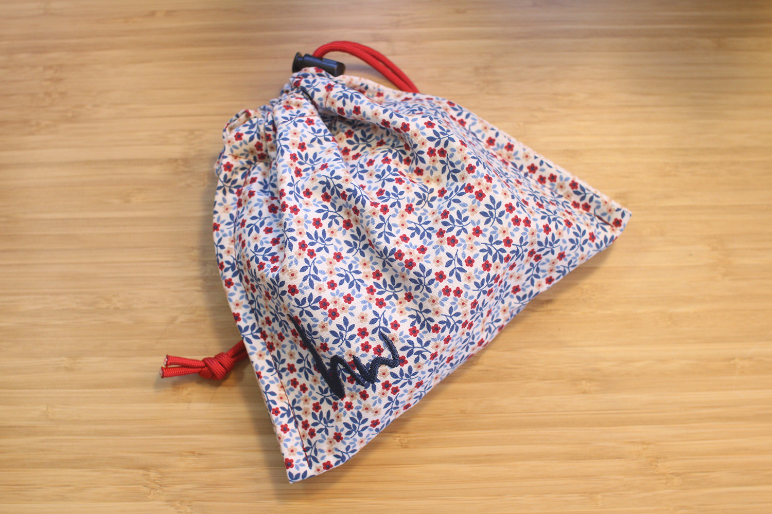 The macropad's hand-sewn and branded drawstring pouch sits on a desktop.