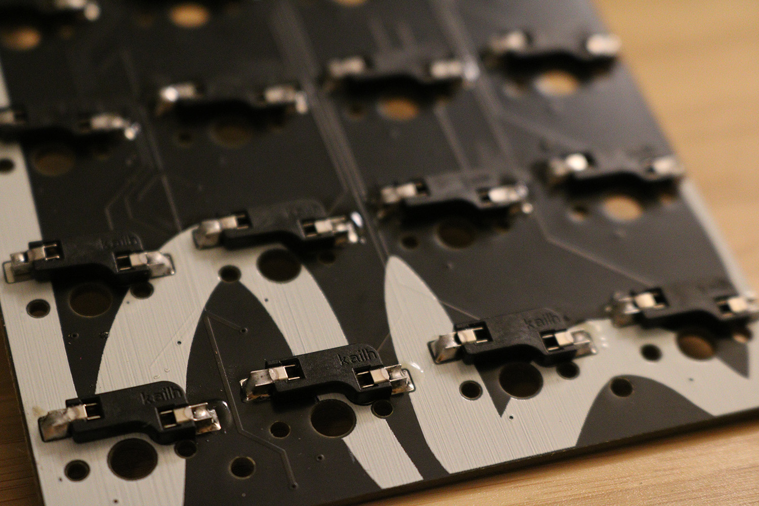 Close-up view of the printed circuit board shows a large screenprinted logo and hot-swap sockets for key switches.